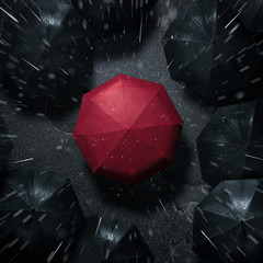 Standing out from the crowd, high angle view of red umbrella between many dark ones in the rain