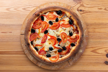 hearty italian pizza on a wooden board. .crispy cheese pizza with tomatoes, olives and mushrooms
