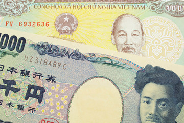 A macro image of a Japanese thousand yen note paired up with a yellow one thousand dong bill from Vietnam.  Shot close up in macro.