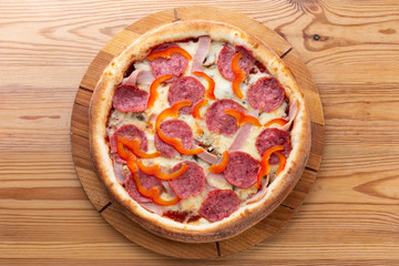 hearty italian pizza on a wooden board. .pizza with salami, fresh pepper and ham