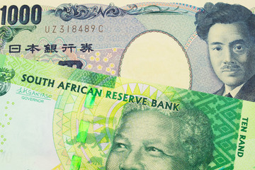 A macro image of a Japanese thousand yen note paired up with a shiny, green 10 rand bill from South Africa.  Shot close up in macro.
