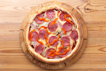 hearty italian pizza on a wooden board. .pizza with salami, fresh pepper and ham