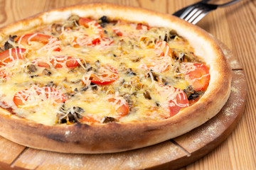 hearty italian pizza on a wooden board. .meat pizza with beef, fresh tomatoes, mushrooms and grated cheese