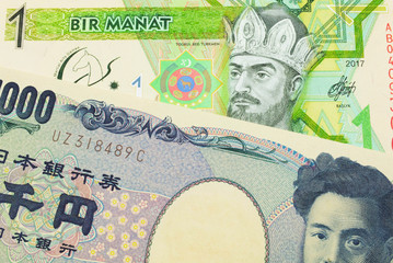 A macro image of a Japanese thousand yen note paired up with a green and yellow one manat note from Turkmenistan.  Shot close up in macro.