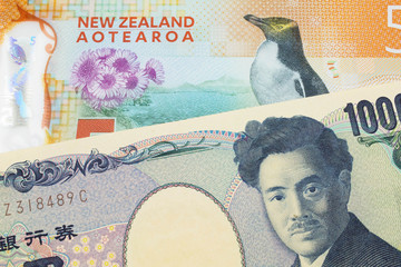 A macro image of a Japanese thousand yen note paired up with a orange, plastic five dollar bill...