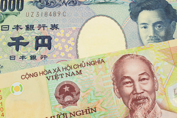 A macro image of a Japanese thousand yen note paired up with a colorful, plastic ten thousand dong note from Vietnam.  Shot close up in macro.