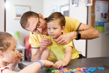 papà aiuta il figlio a mettersi la polo gialla come la sua in contesto familiare