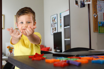 bambino con polo gialla usa fa il gesto di "spiderman" giocando divertito  © alex.pin