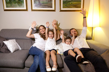 gruppo familiare alza le braccia allegramente a casa nel divano 