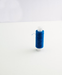 a spool of blue sewing thread on a white background