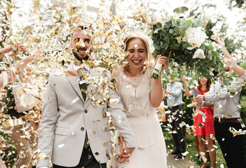 wedding confetti,newlyweds are greeted with festive confetti,joyful bride and groom go on a wedding day in the rain with confetti