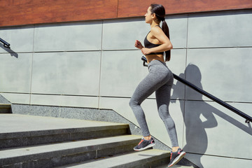 sportive young brunette woman walking on stairs. Beautiful fitness girl in stylish sportswear outdoors. sport and healthy lifestyle concept.