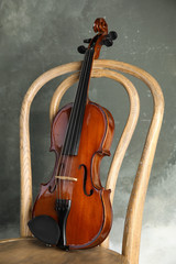 Classic violin on chair against grey background
