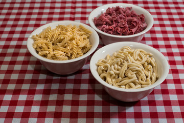 Raw italian pasta in a red and white towel background top view