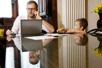 padre lavora al computer in casa in modalità  smart working mente figli giocano con il tablet