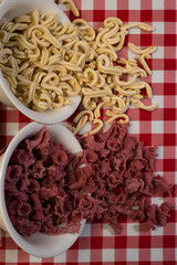 Raw italian pasta in a red and white towel background top view