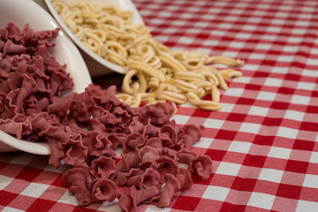 Raw italian pasta in a red and white towel background top view
