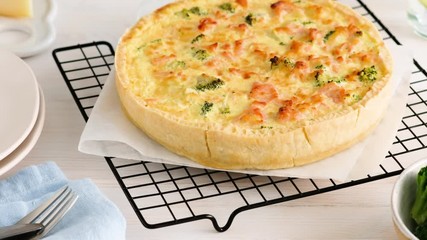 Woman serves quiche (pie) with goat cheese, salmon, broccoli baked in the oven. Serving quiche on the table. - Powered by Adobe