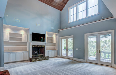 Beautiful open living room with high ceilings, fireplace, and view windows.
