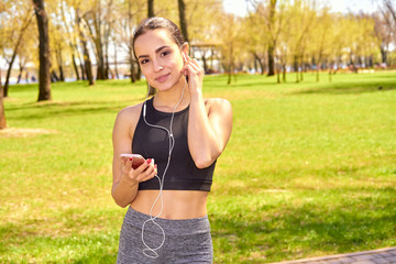 Runner girl holding smartphone using touchscreen for choosing music or texting sms on app before running on track. Smartphone apps concept. Female athlete woman.