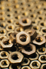 Close-up, macro. Old soviet brass nuts. Texture, background of brass nuts laid out in the form of honeycombs. Nuts of gold color. Dirty nuts in oil. Brass scrap metal