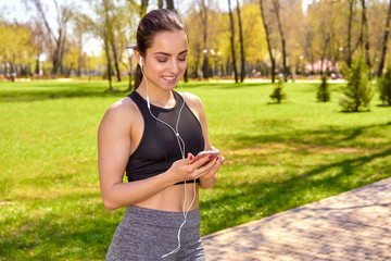 Runner girl holding smartphone using touchscreen for choosing music or texting sms on app before running on track. Smartphone apps concept. Female athlete woman.