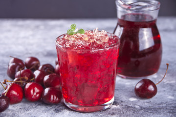 Glass with fresh homemade cherry sweet iced tea or cocktail, lemonade with mint. Refreshing cold drink. Summer party.