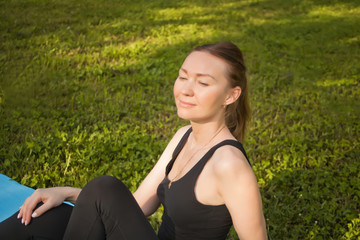 Naklejka na ściany i meble Active sporty woman sitting on a sport mat and relaxing after training outdoors.