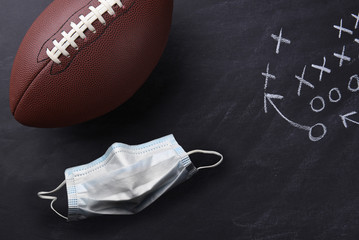 Covid-19 surgical mask and an American style football on a chalkboard with a play diagramed.