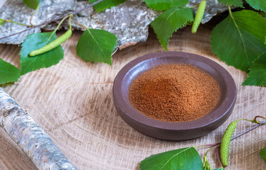 Chaga tea mushroom from birch tree using for healing tea
Powdered chaga on a ceramic brown plate with green birch leaves and birch bark on a wooden background