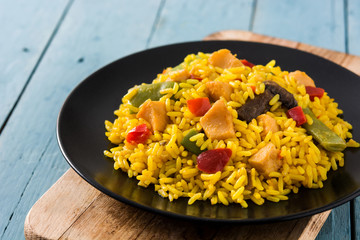 Fried rice with chicken and vegetables on black plate on blue wooden table