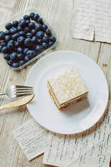 Honey cake with blueberries in a white saucer on the table