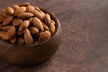 Bowl Full of Raw Natural Almonds on a Dark Wood Table