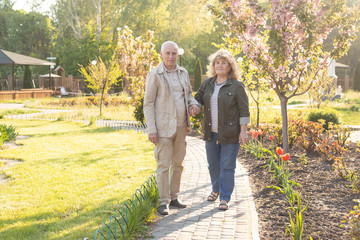 Obraz premium Active seniors on a walk in summer park, senior couple relax in spring summer time. Healthcare lifestyle elderly retirement love couple together valentines day concept