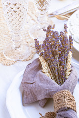 Beautiful and elegant wedding table decor in provence style. France. decoration with dry lavender flowers, oats, rustic ribbon and napkin, glasses for champaign. Romantic and luxury