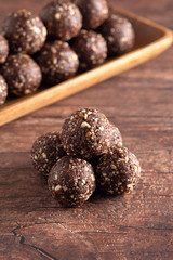 Chocolate Energy Protien Balls Made of Raw Organic Nuts and Dates on a Wooden table