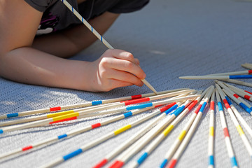 Kind spielt Spiel Mikado mit großen Holzstäben pick-a-stick