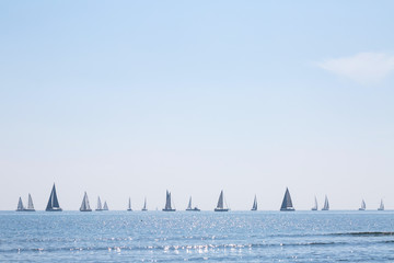 Many sail yachts in the sea in the backdrop bright sunshine. Calm weather. Romantic magical summer.