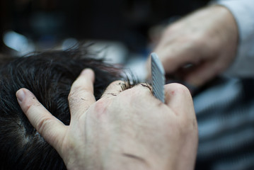 Naklejka premium Closeup of barber hands cutting hair