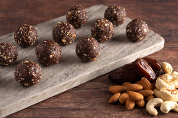 Chocolate Energy Protien Balls Made of Raw Organic Nuts and Dates on a Wooden table