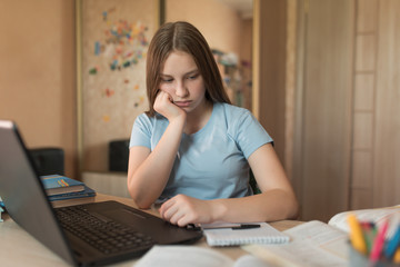 Sad and tired, teenager girl of 12-14 years old, offended at home by depression, laptop lessons....
