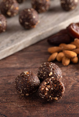 Chocolate Energy Protien Balls Made of Raw Organic Nuts and Dates on a Wooden table