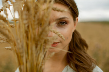 Portrait of a lovely pleasant woman who holds her hair with her hand, which is blown by the wind. She stands on the roof and smiles. © Anton