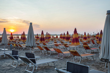 Italy ,summer ,empty deck chairs are on the beach at sunset, picture without people, clear proportions, geometry