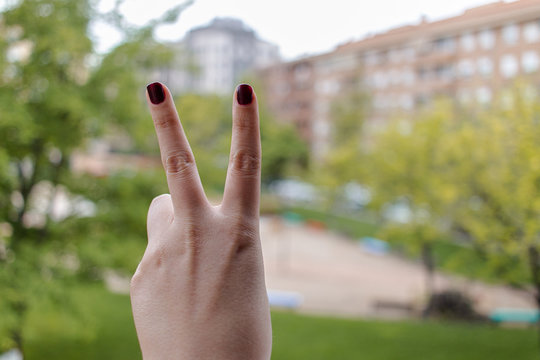 Woman's hand is show two fingers up isolated on land background. Finger symbols of peace strength fight, victory symbol, letter V in sign language or number two or second. Clipping Path.