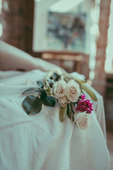 A close-up composition of white roses and purple hyacinth on a linen sheet. Floral and wellness concept. Tender morning decor. Flowers on a white tablecloth and silhouette of female legs.. Soft focus