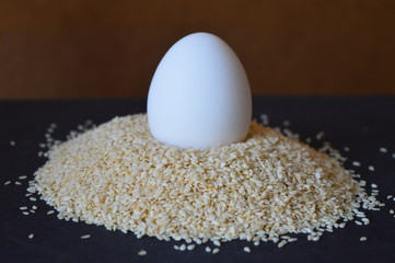 white egg in a sesame seeds  on a black table