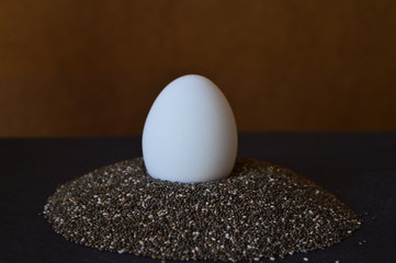 white egg in a chia seeds  on a black plate