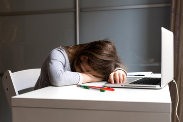 Asleep sitting at the Desk at the laptop girl. Tired child from distance learning at home. Online...