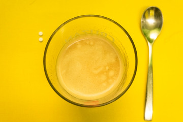 Vaso de café con una cuchara y sacarina / edulcorante sobre una superficie amarilla